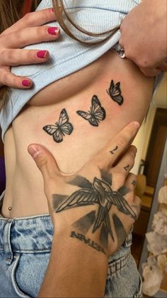 a woman's stomach with butterflies on it and her hand in front of her belly