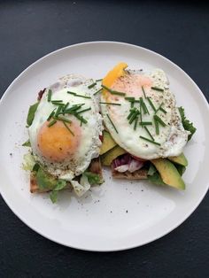 two eggs are on toast with avocado and lettuce in the middle