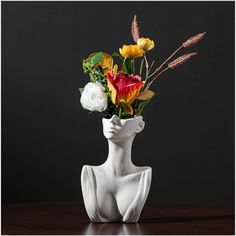 a vase with flowers in it sitting on a table next to a black wall,