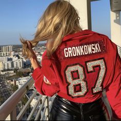 a woman wearing a red jacket with the number 89 on it is looking out over a city