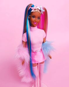 a barbie doll with pink and blue hair on top of a white pedestal in front of a pink background