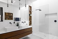 a modern bathroom with two sinks and a shower stall in the middle, surrounded by wooden cabinets