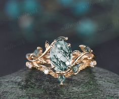 a ring with green and white stones on it's sides, sitting on top of a rock