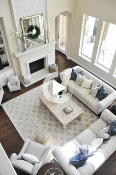 an aerial view of a living room with white furniture and blue pillows on the couches