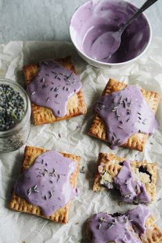 crackers with purple icing and sprinkles on them next to a bowl of dip