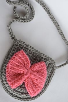 a crocheted purse with a pink bow on the front and grey trim around it