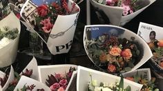 many flowers are arranged in white bowls on the table with pictures and cards attached to them