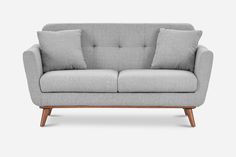 a grey couch with two pillows on it and a wooden frame around the armrests