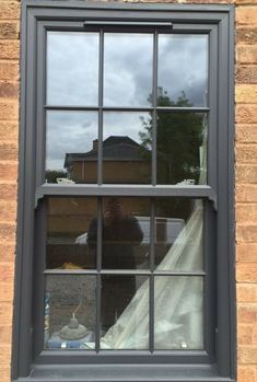 the reflection of a man in a window on a brick building with a tarp covering it