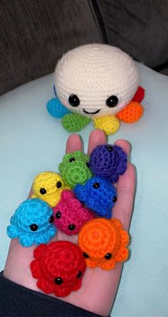 a hand is holding small crocheted items in the shape of fish and turtle