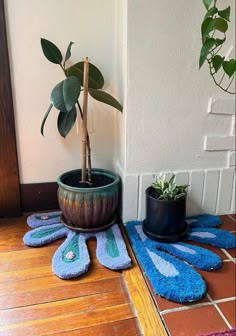 a potted plant sitting on top of a wooden floor next to blue rugs