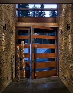 an entrance to a home with stone walls and wooden doors that lead into the outside