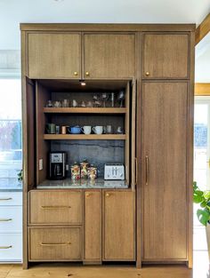 an open cabinet in the middle of a kitchen with lots of cupboard space and drawers