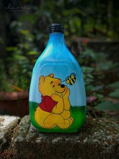 a blue glass bottle with a cartoon winnie the pooh on it sitting on a rock