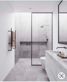 a modern bathroom with marble counter tops and white walls, along with a walk - in shower