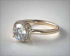 a white gold ring with a cushion cut diamond in the center and pave set shoulders