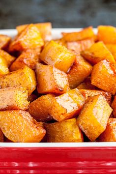 a red and white dish filled with cubed sweet potatoes on top of a table