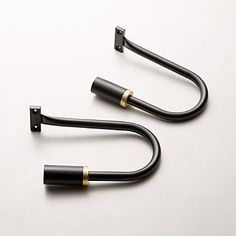 two black and gold handles on a white surface with no one in the photo looking at them