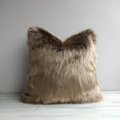 a furry pillow sitting on top of a wooden floor next to a wall with white paint