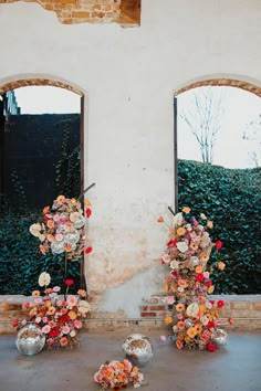 flowers are arranged on the ground in front of two windows