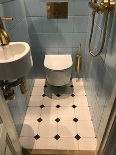 a bathroom with blue walls and black and white tile flooring, gold faucet