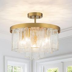 a chandelier hanging from the ceiling in a room with white walls and windows