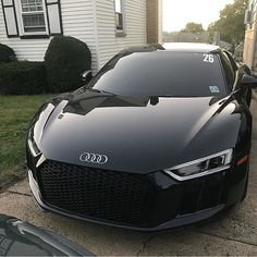 a black sports car parked in front of a house with the number 26 on it