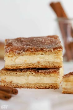 three cheesecake bars stacked on top of each other with cinnamon sticks in the background