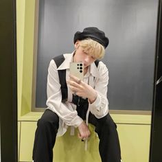 a young man sitting on top of a toilet holding a cell phone in his hand