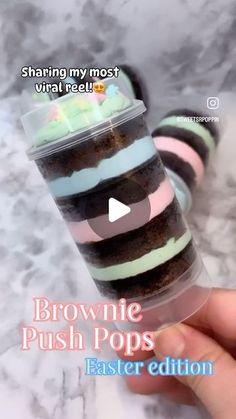 someone holding a cup with brownie push pops in it