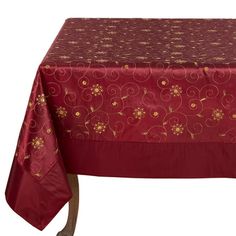 a red table cloth with gold flowers on it and a white wall in the background