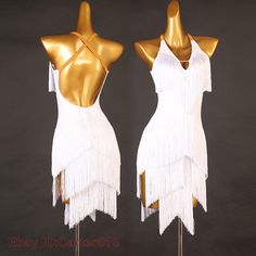 two mannequins dressed in white and gold with tassels on them