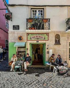 people are sitting outside on chairs in front of a small building with many windows and balconies