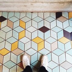 a person standing on a tiled floor with their feet up