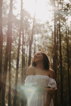 a woman is standing in the woods with her eyes closed and she's smiling