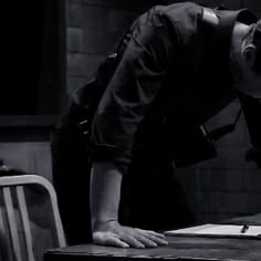 black and white photograph of a man leaning over a table