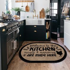 a kitchen with black cabinets and white walls has an area rug that says, welcome to the kitchen we are made here