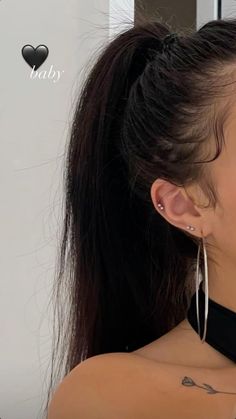 a woman with long hair wearing large silver hoop earrings and a black halter top