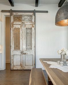 an old door is opened to reveal a dining room with white walls and wood floors