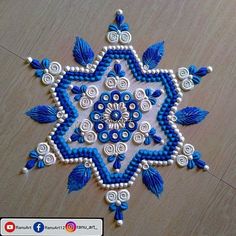 a blue and white beaded snowflake on a wooden surface