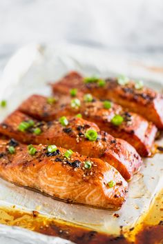 three pieces of cooked salmon sitting on top of a piece of wax paper covered in seasoning