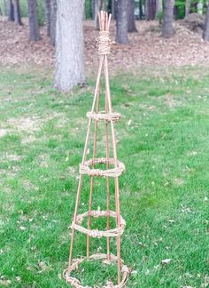 a tall metal tree with lots of branches on top of it in the grass next to some trees