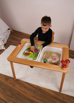 a little boy that is sitting in a chair with some food on the trays