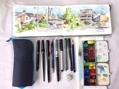 an artist's kit with watercolors, pens and pencils in it