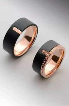 two black and gold wedding bands, one with a cross on the inside of it