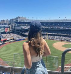 a woman sitting in the bleachers at a baseball game looking out into the stands