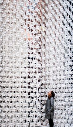 a person standing in front of a wall made out of white plastic cups and chains