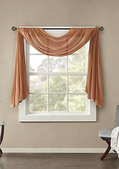 a living room with a couch, chair and window covered in orange drapes