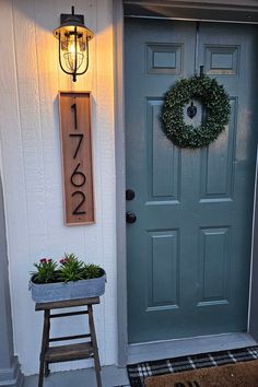 a blue front door with a wreath on it and a number sign above the door