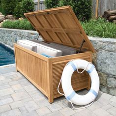 an outdoor storage box with a life preserver on the ground next to a swimming pool